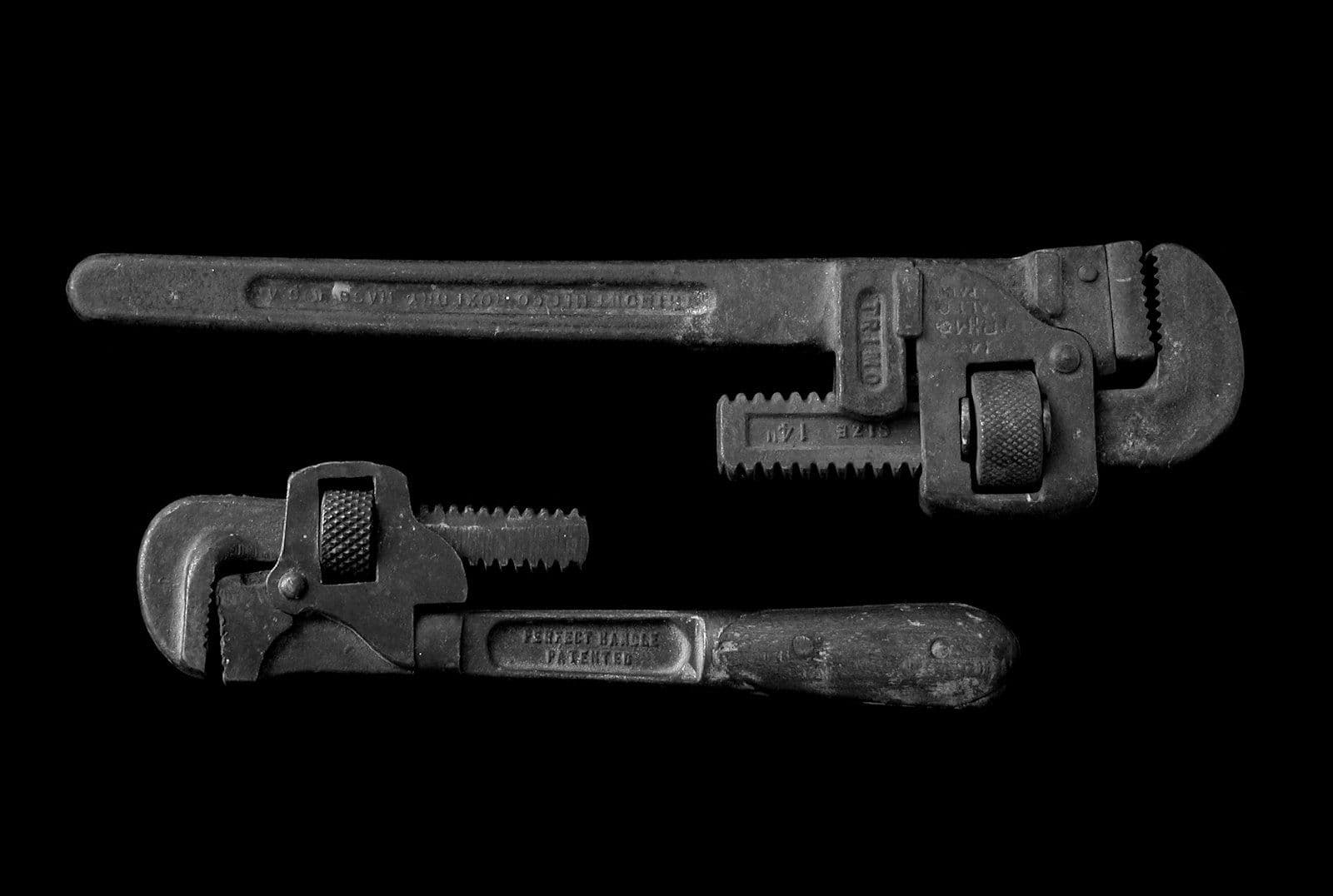 Two adjustable pipe wrenches on a dark background — A plumber's guide to getting found online in Houston