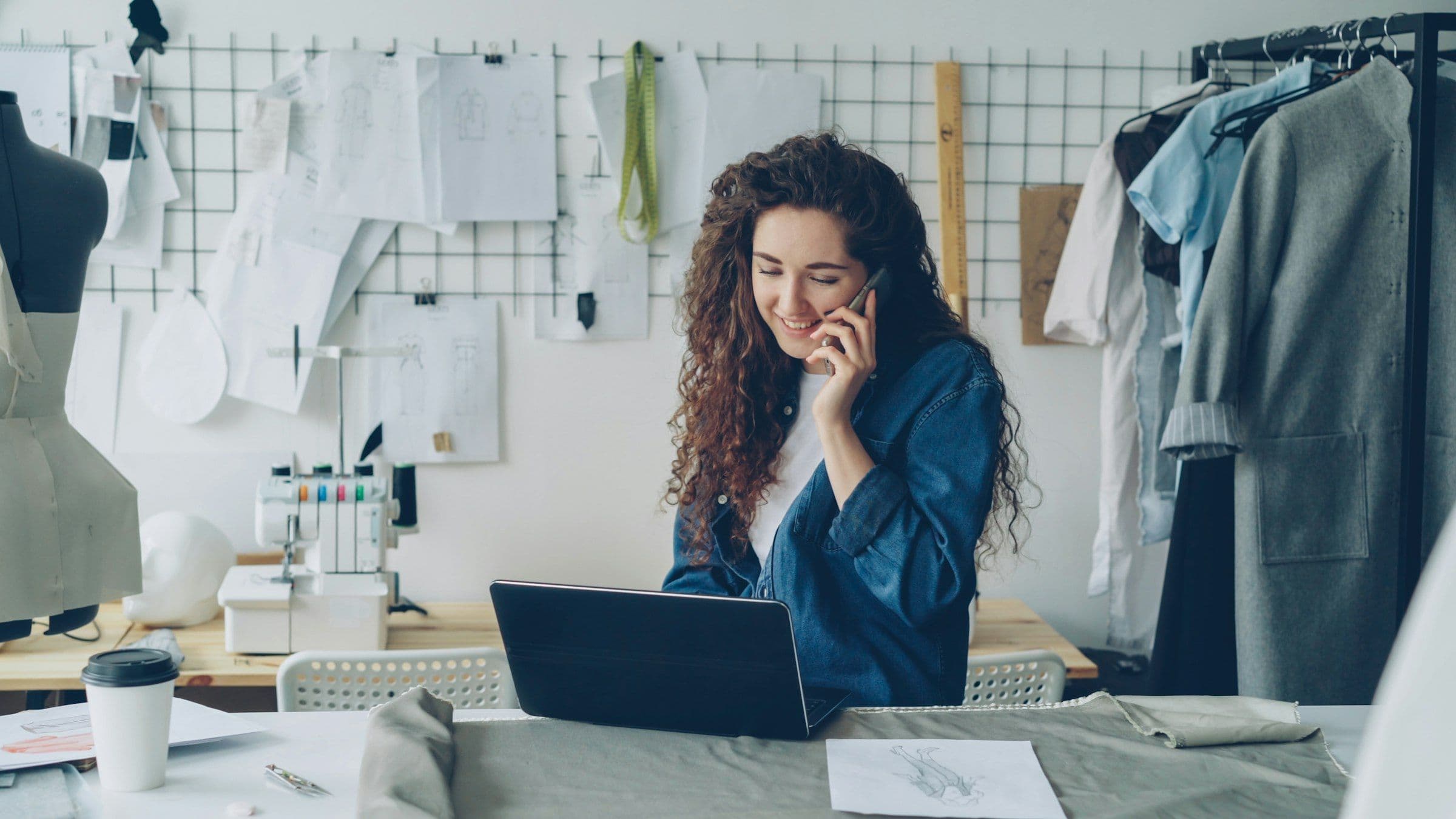 A small business owner on the phone, working on a laptop in a design studio